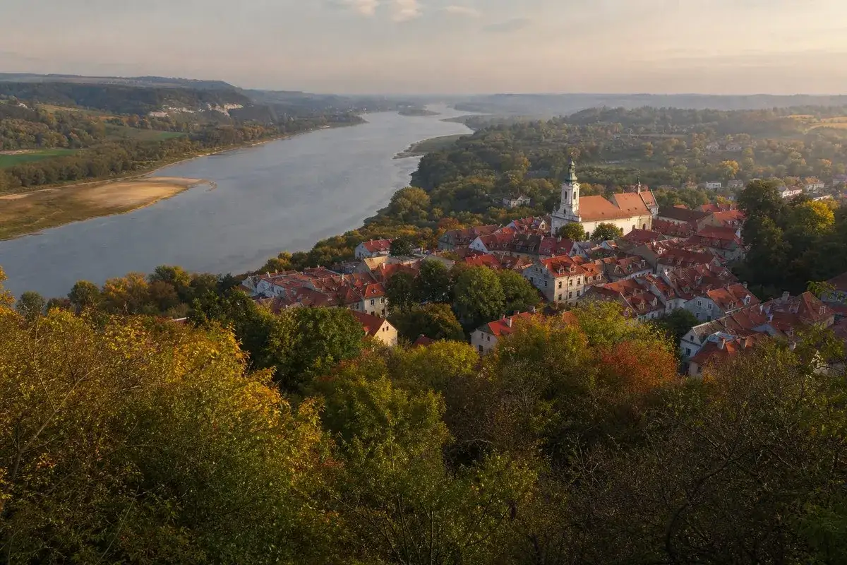 Widok na Kazimierz Dolny z Wisłą i jesiennymi drzewami. Widać kościół i urokliwe kamienice, które są głównymi kazimierz dolny atrakcje.