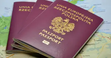Polskie paszporty na tle mapy. Zastanawiasz się, ile kosztuje wyrobienie paszportu?