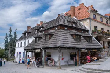 Kazimierz Dolny atrakcje: urokliwy rynek z kamieniczkami, lodziarnią i sklepikami. Ludzie spacerują, ciesząc się atmosferą.